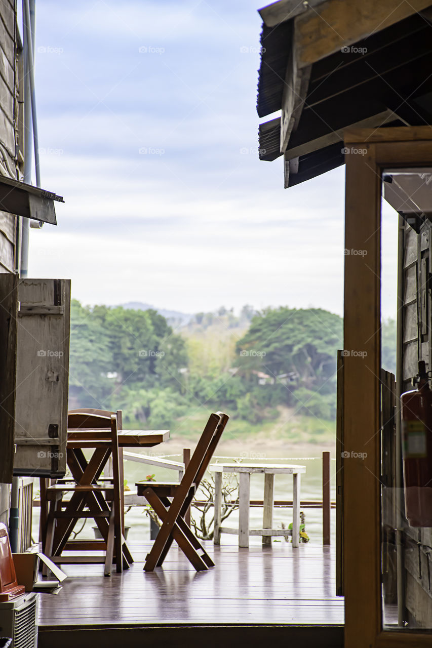 Wooden chairs on the balcony. Background on the Mekong River and the trees at Walking Street Chiang Khan, Loei in Thailand.