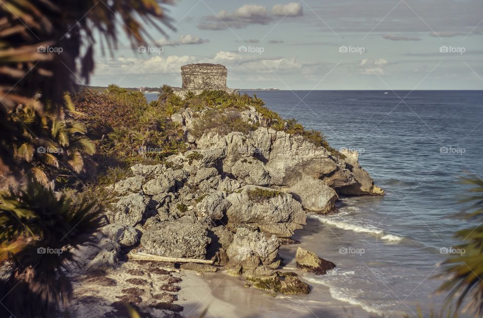 Rocky promontory overlooking the Caribbean Sea with an ancient Mayan building on top: Watchtower of the Mayan complex of Tulum in Mexico.