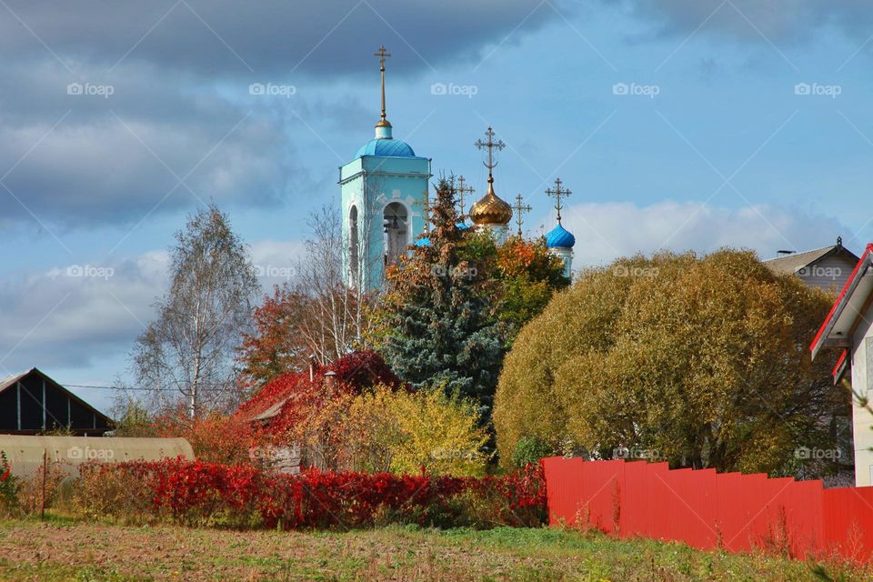 blue church and autumn trees of different colors