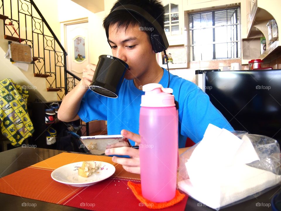 young teen eating snack while watching on a mobile device