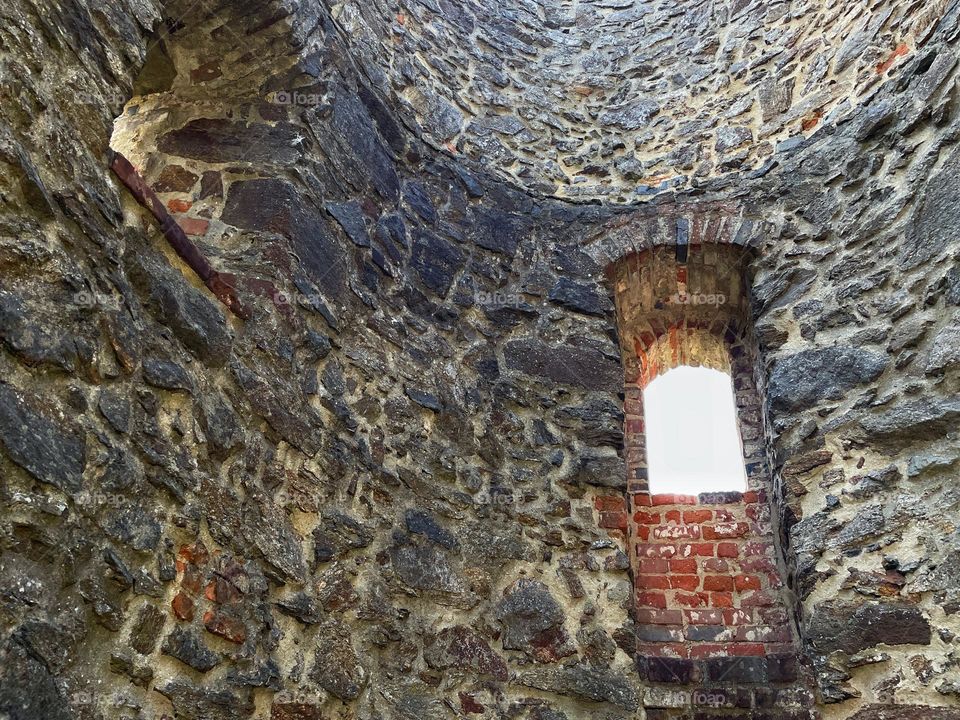 Historical round stone wall with window opening of a vault in a castle