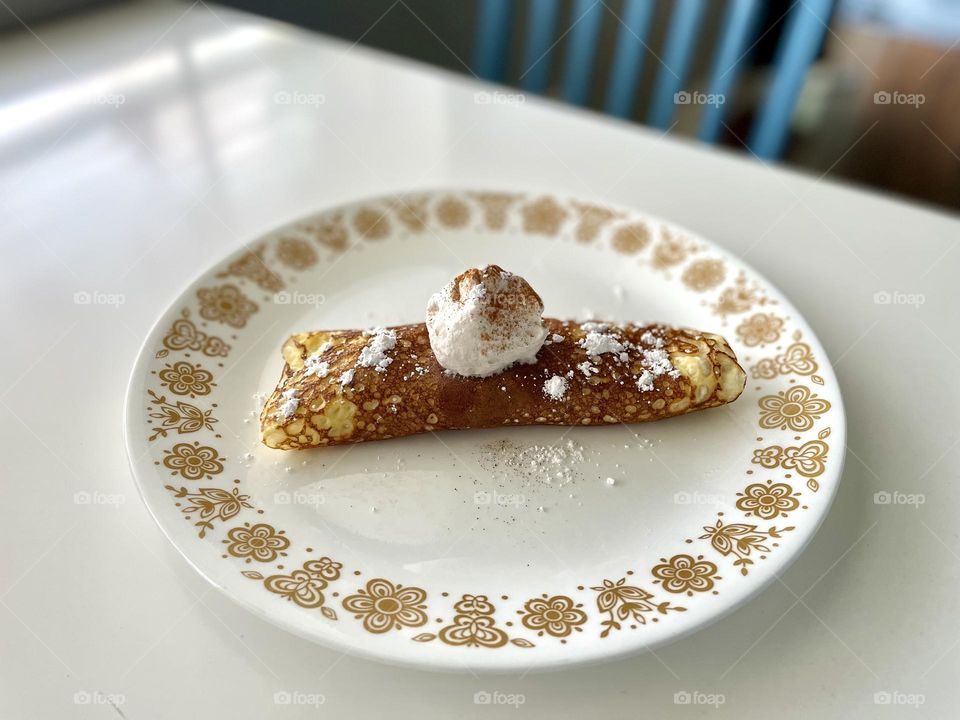 Delicious peaches and cream crepe on a plate, making crepes at home, homemade crepe on a plate in the kitchen, cooking crepes with kids