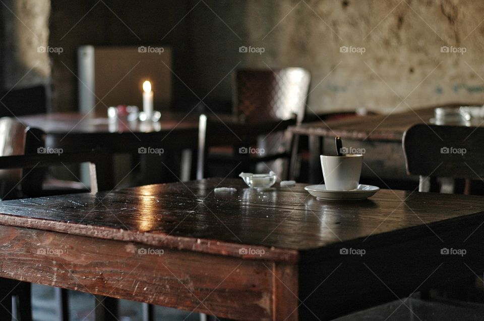 Coffee on wooden table in cafe. White coffe cup standing on wooden table in cafe