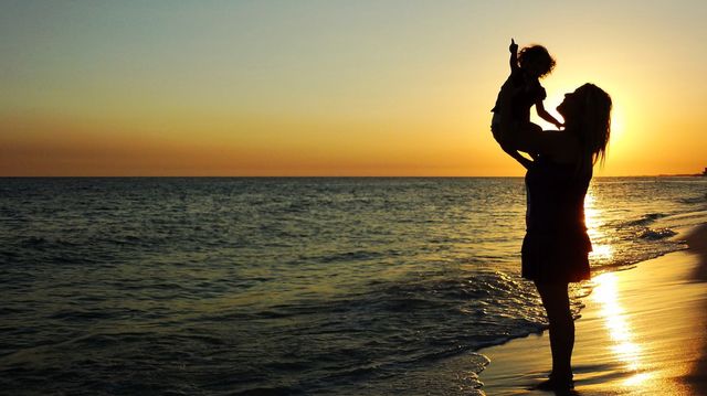 Fun day at the beach. Mom and a baby enjoying the sand and sun