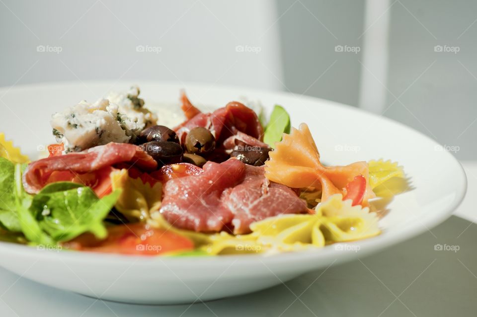 close-up of a young man eating a salad in a light kitchen