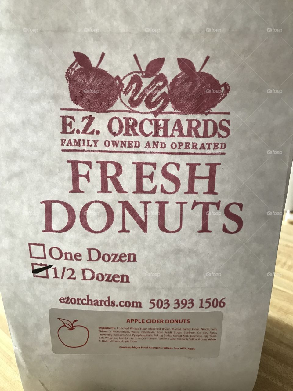 A white paper bag filled with a half dozen freshly made donuts from a farm market 