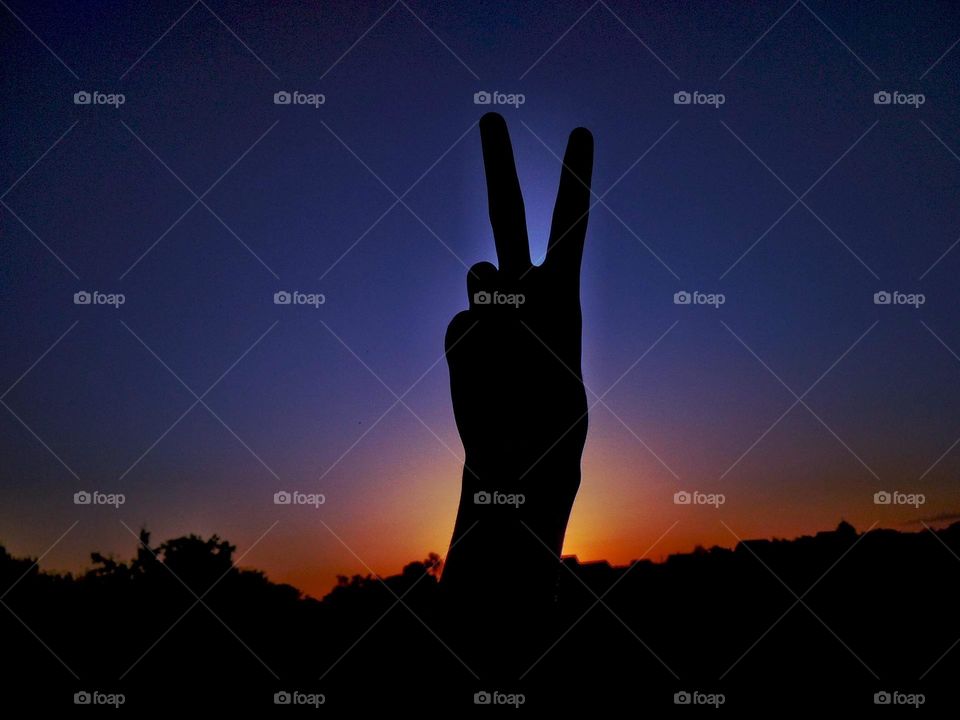 Peace sign on sunset background