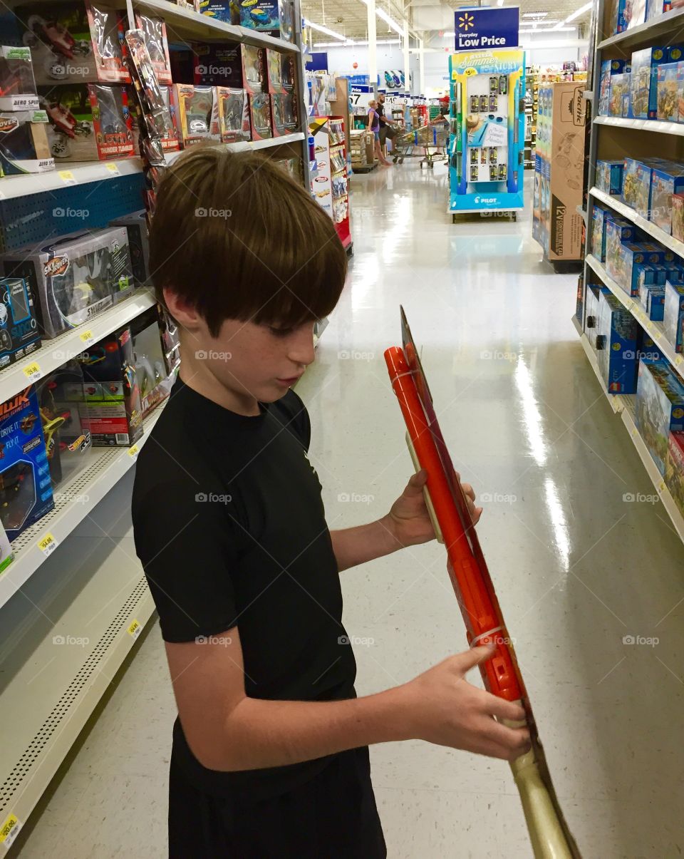 Young boy looking at a toy in the store studying it real good!