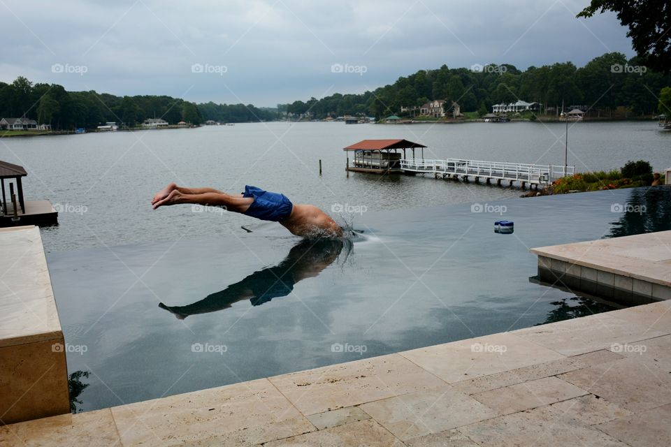 Male adult diving into a lakefront infinity pool