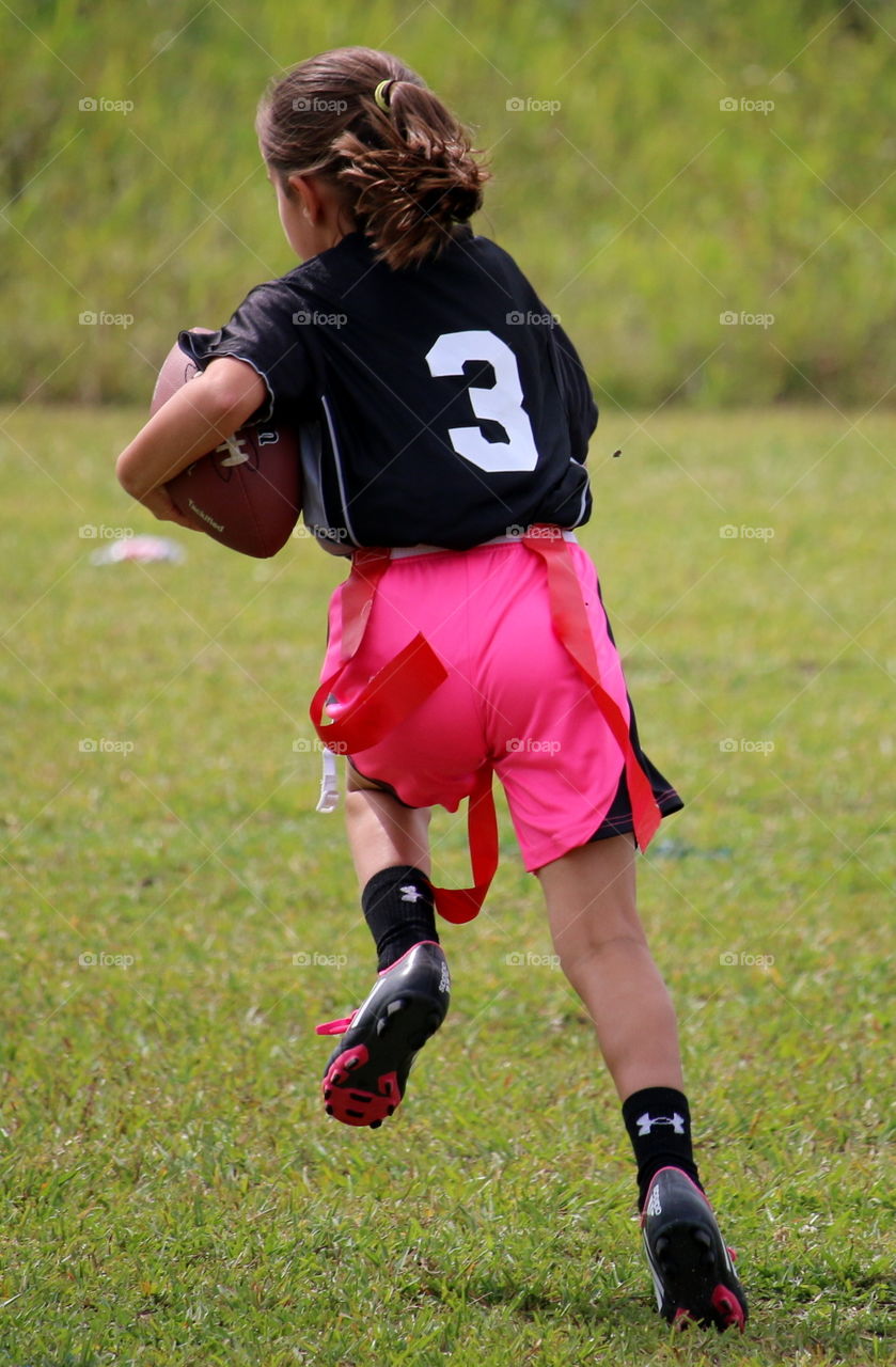 Flag football fun - girl running with the football