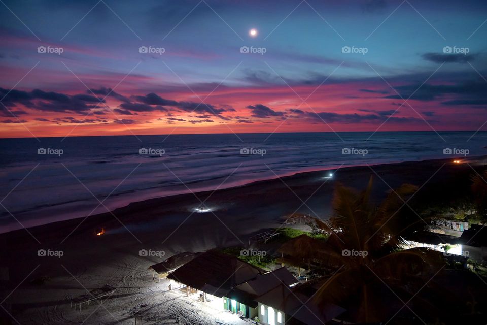 Parangtritis beach at dusk, the atmosphere of the sky is a little cloudy which is illuminated by the sunset adding to the blue sky and sea. The lights in several houses and buildings on the beach began to light up. My instagram : @dodhoy_cikuray