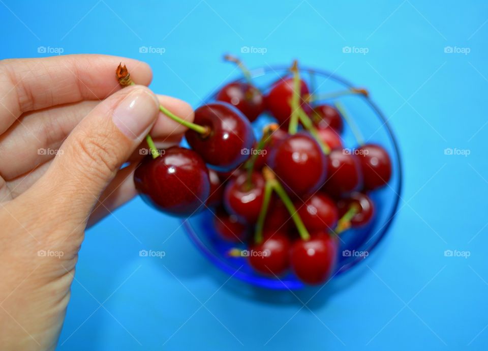 red cherry on a plate in the hand blue background