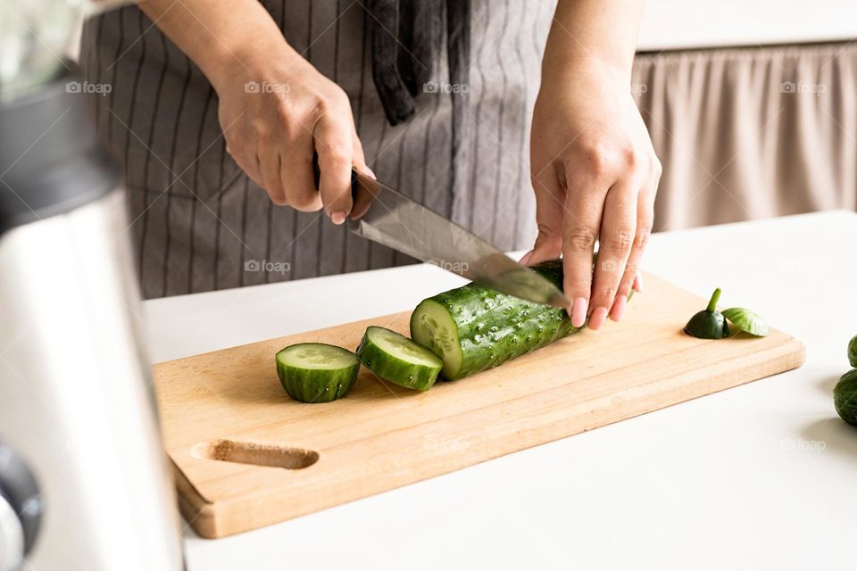 woman cutting cucumber at kitchen