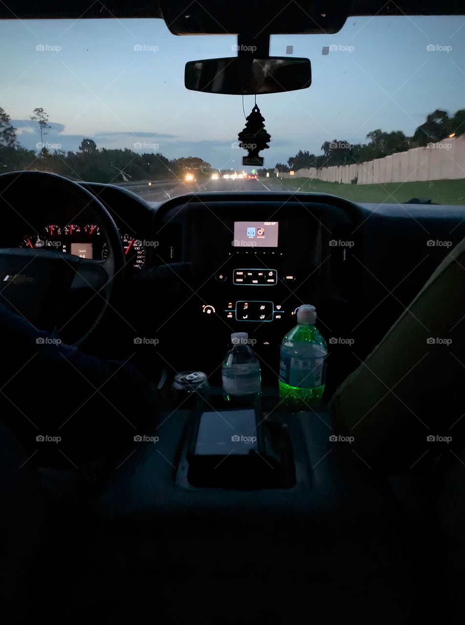 Commuting: in the evening, from a child in the back of the inside of the pickup truck seeing the front with parents, mom and dad sitting in the front seats. Father’s driving with the console and lights from other vehicle through windshield on highway