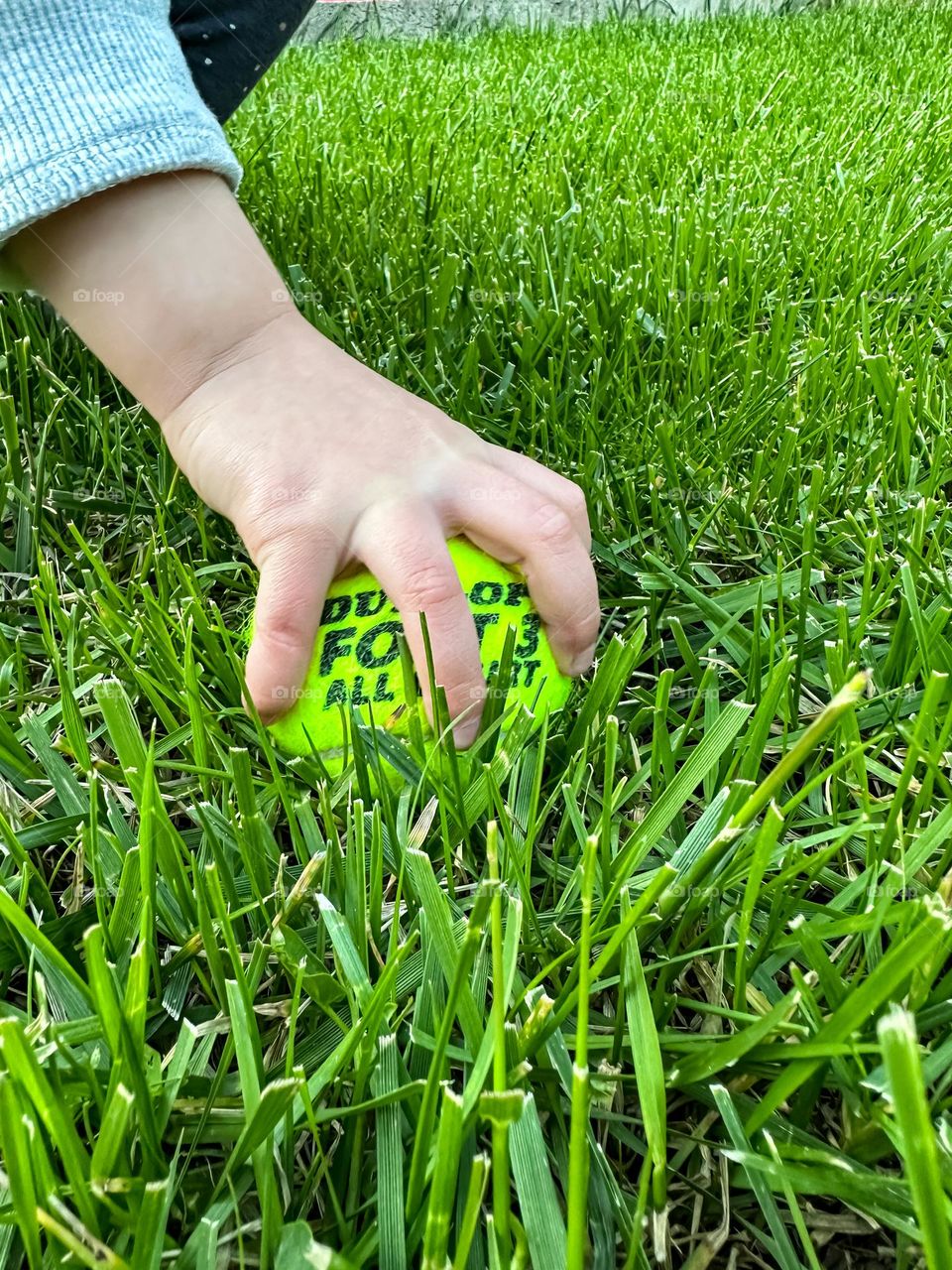 Little hand picking up the tennis ball 