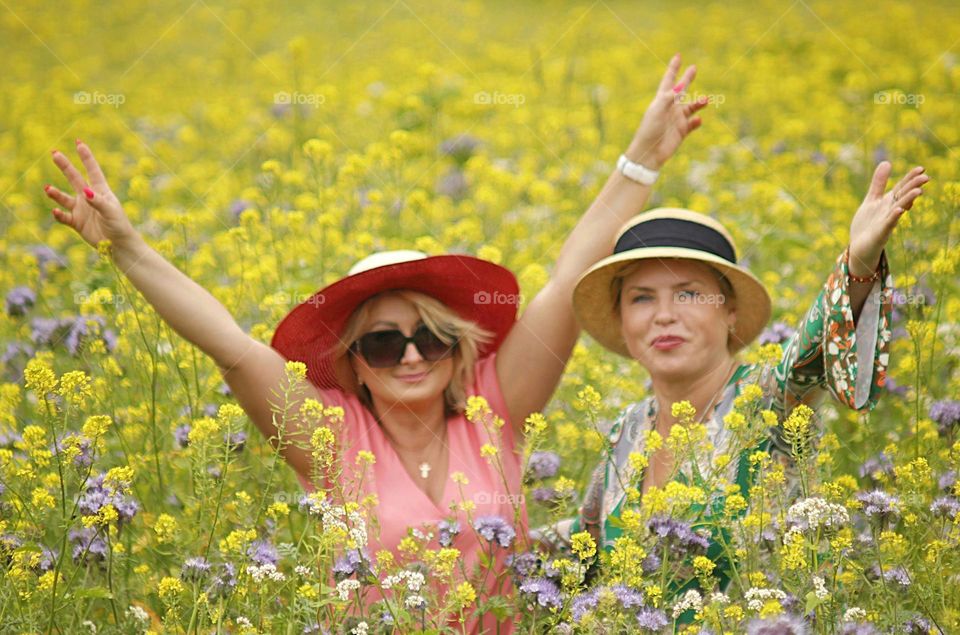 2 women with hats in a yellow rape field