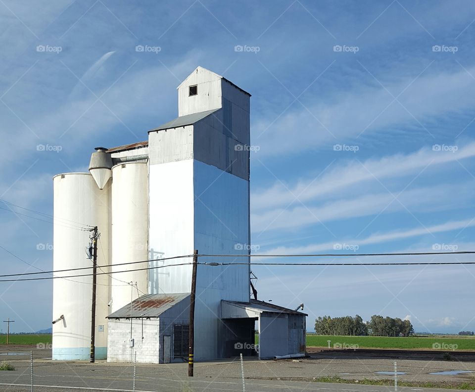 Large silos along a California highway while the sun is setting