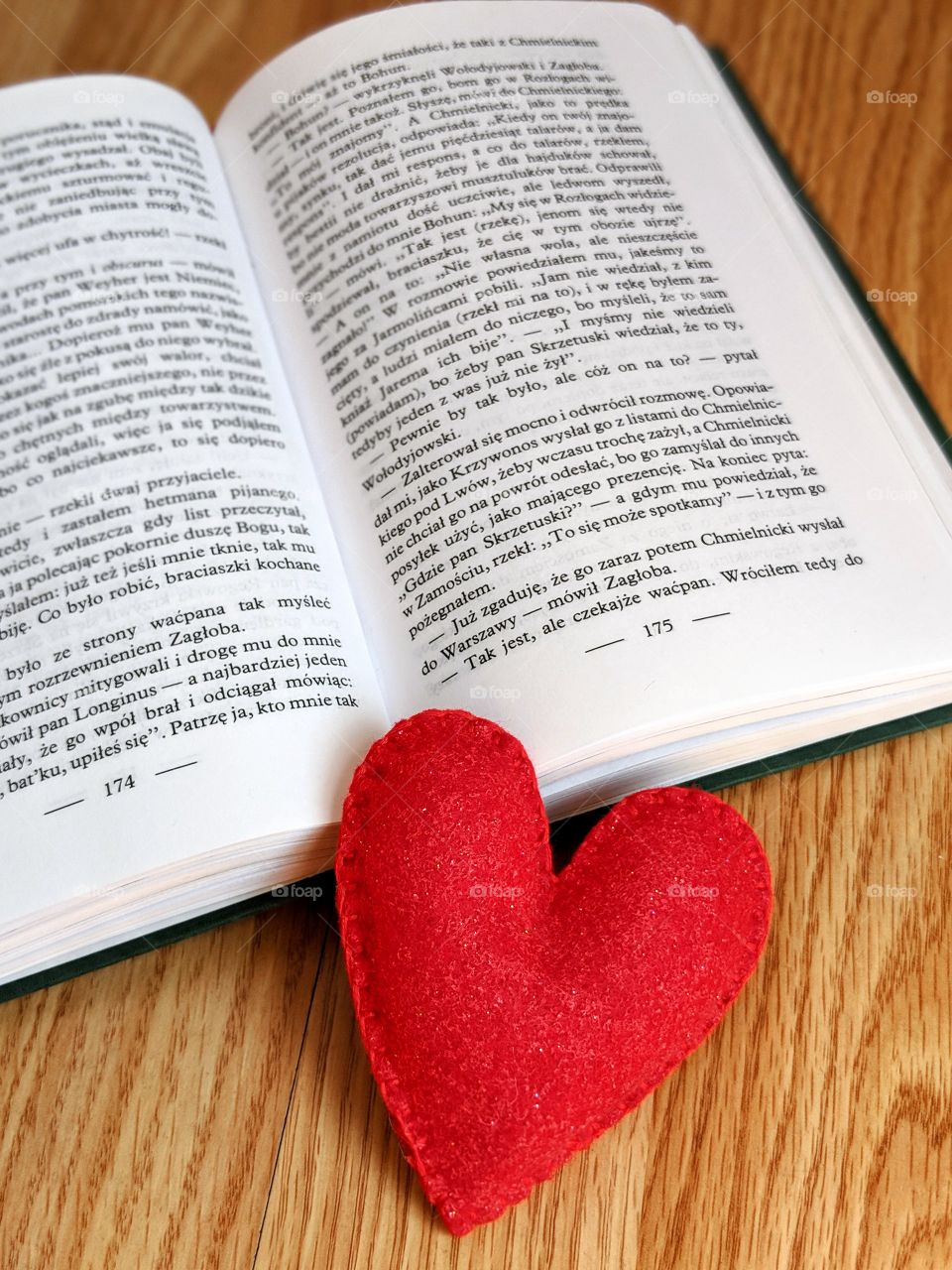 An open book and a red heart on a wooden background
