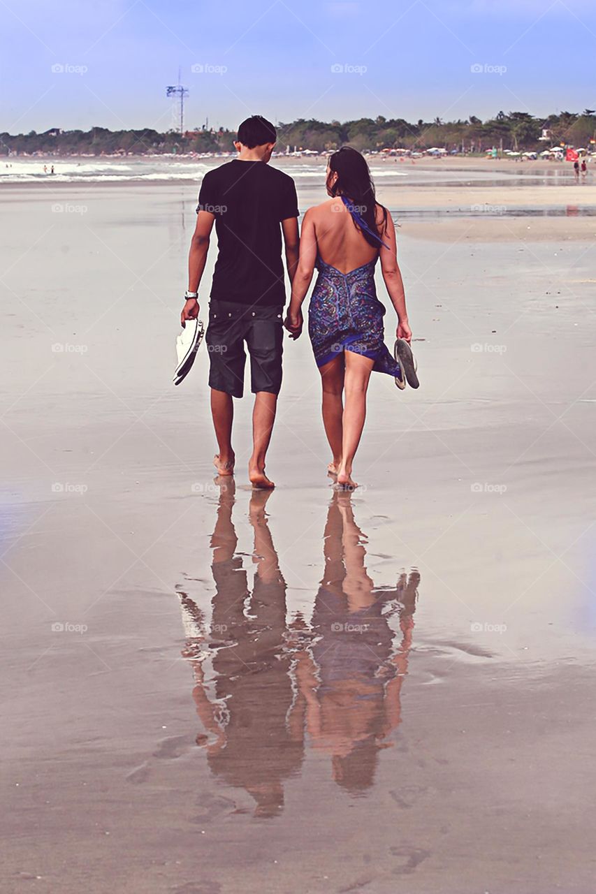 A couple Walk hand in hand along the sea shore as the sun sets