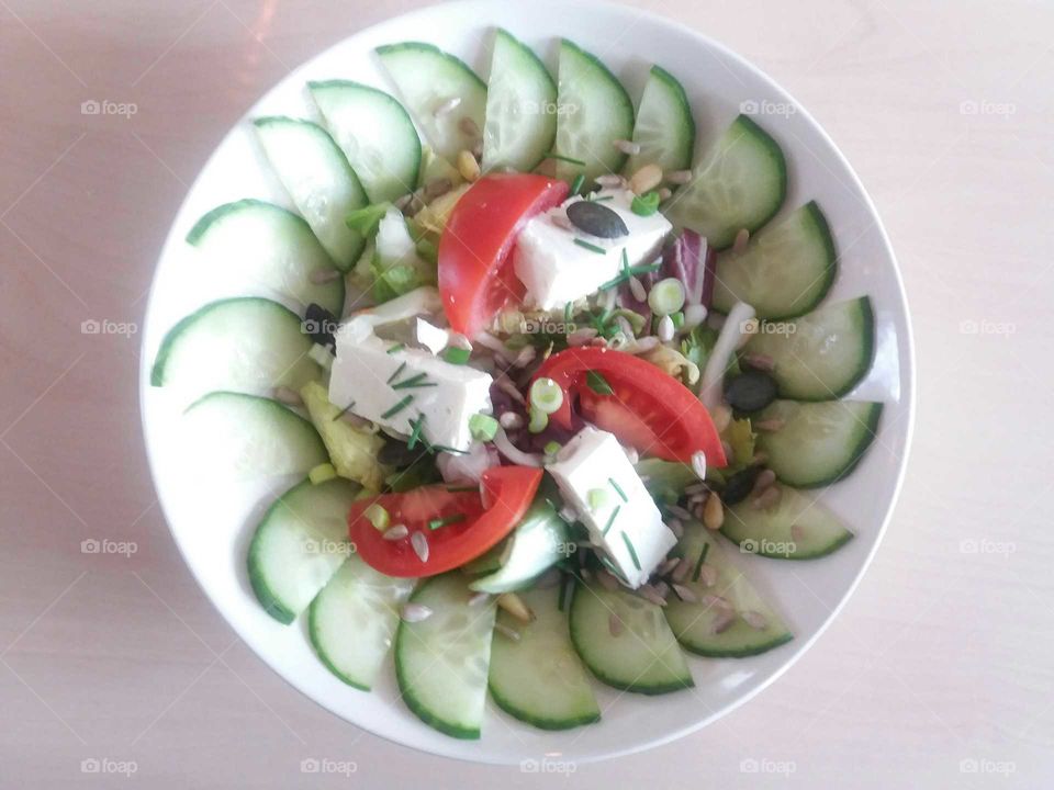 bowl of cucumber  salad with  tomatoes and  cheese