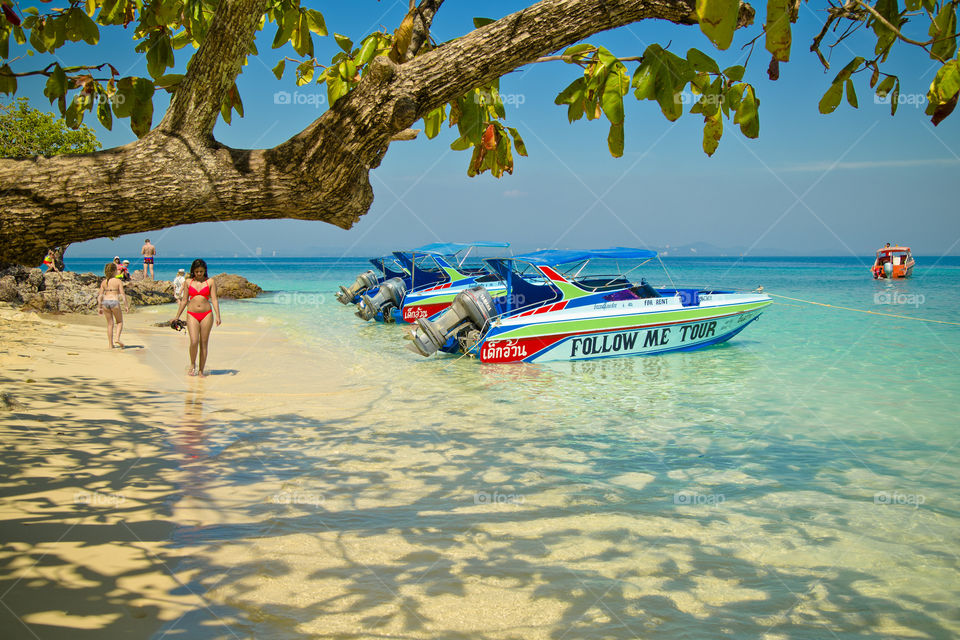 Paradise holidays. girl walking on the beach next to speed boats