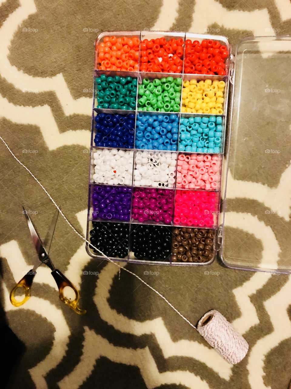 A beautiful and bright colorful box of beads with yarn and scissors to make jewelry with. Necklaces, bracelets, anklets and more.