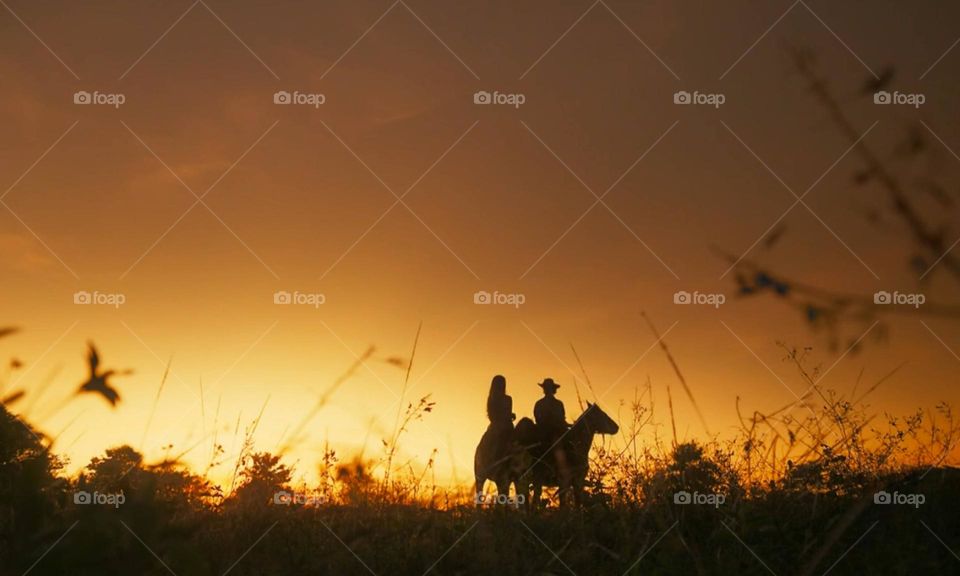 Couple riding horses at sunset