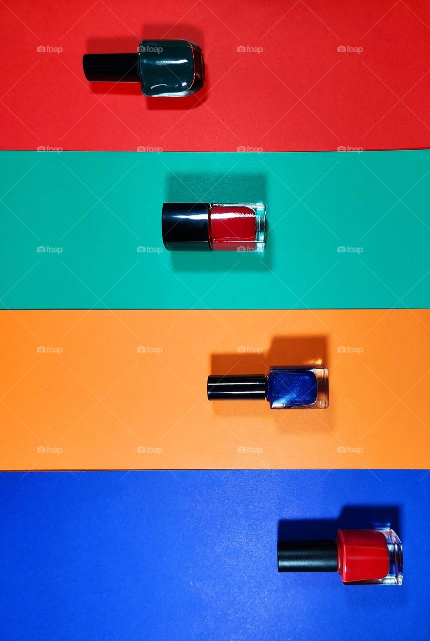 Complementary colours flatlay composed with red, green, orange and blue papers and nail varnishes