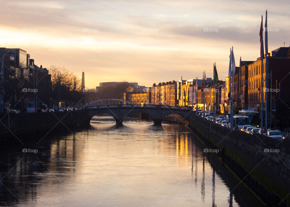 Golden sun rays reflect off of the buildings along the Liffy River in Dublin, Ireland