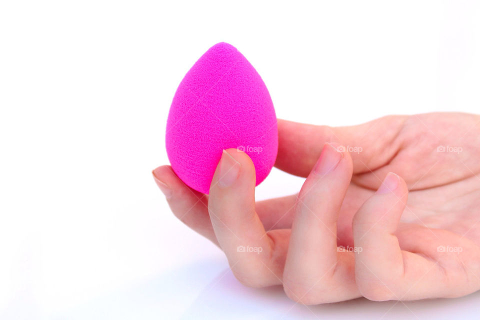 Hand holding a pink makeup sponge