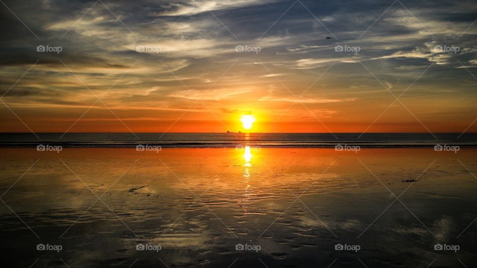 Sunset reflection over ocean with dramatic sky