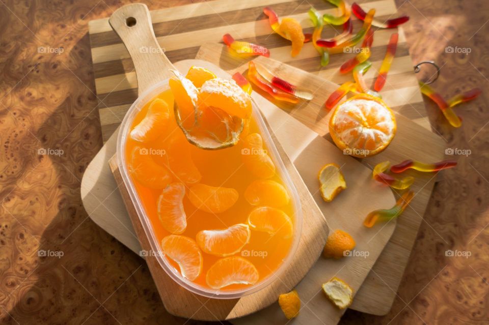 Delicious orange jelly with tangerine slices in a container and jelly worms.