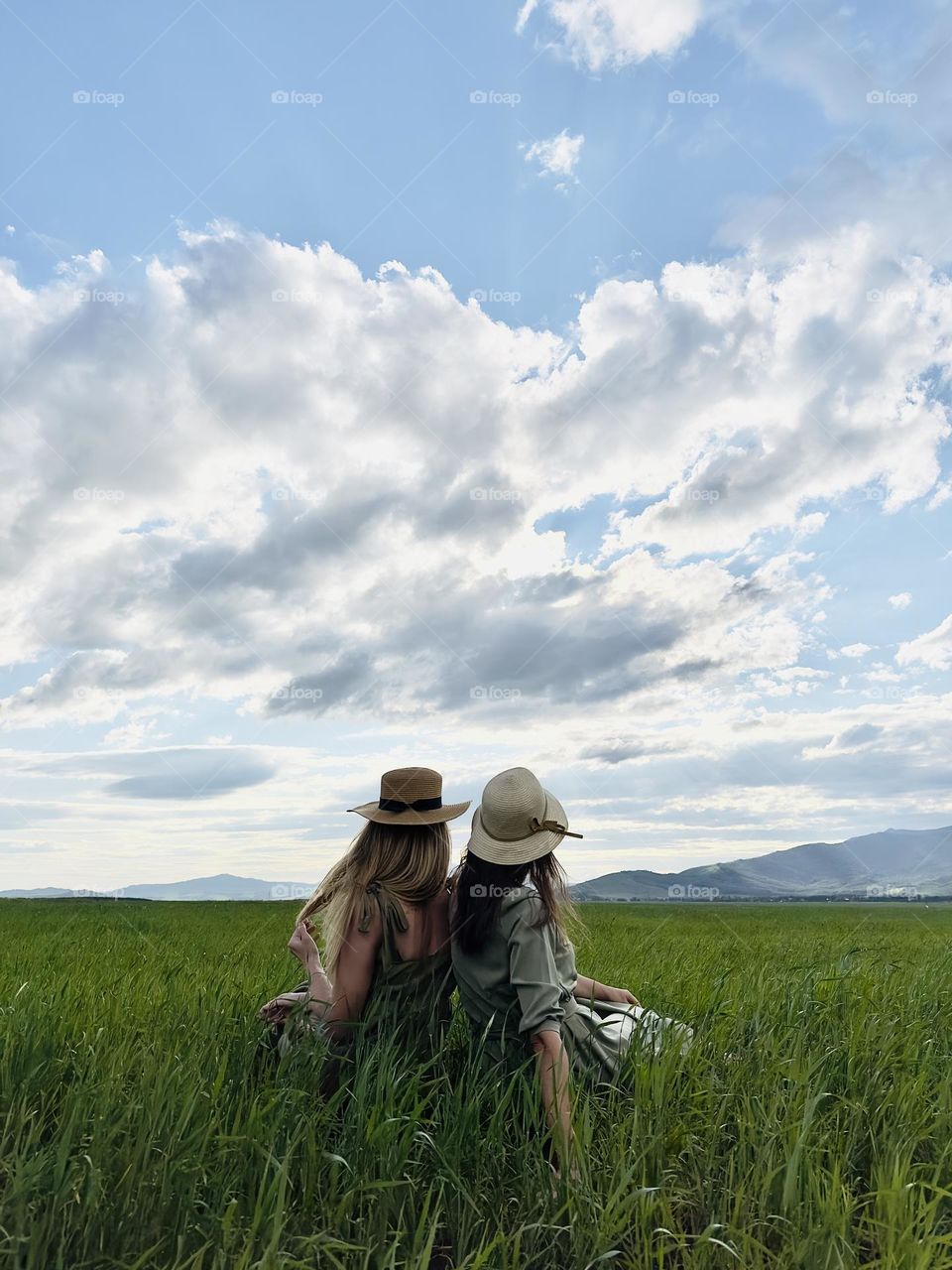 two girls sisters on a picnic in a field looking at the sky