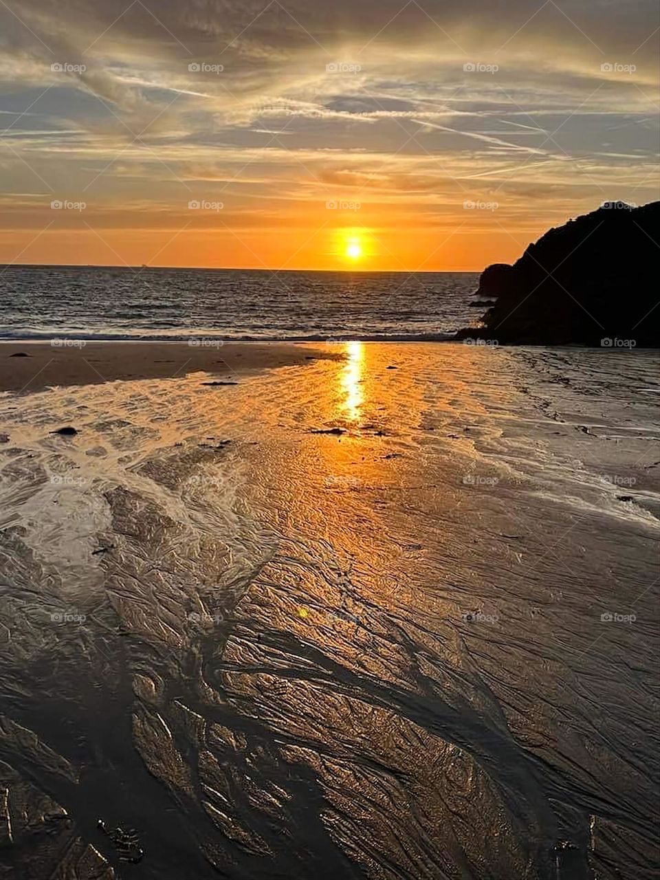 Sunset offering a gradient of orange, grey and brown on Nicet beach and sea in Saint Malo