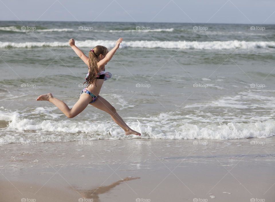 Active and happy girl running on the beach.