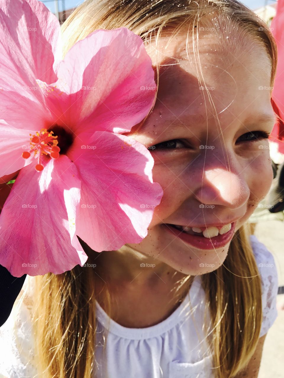 Close-up of a girl with pink hibiscus flower