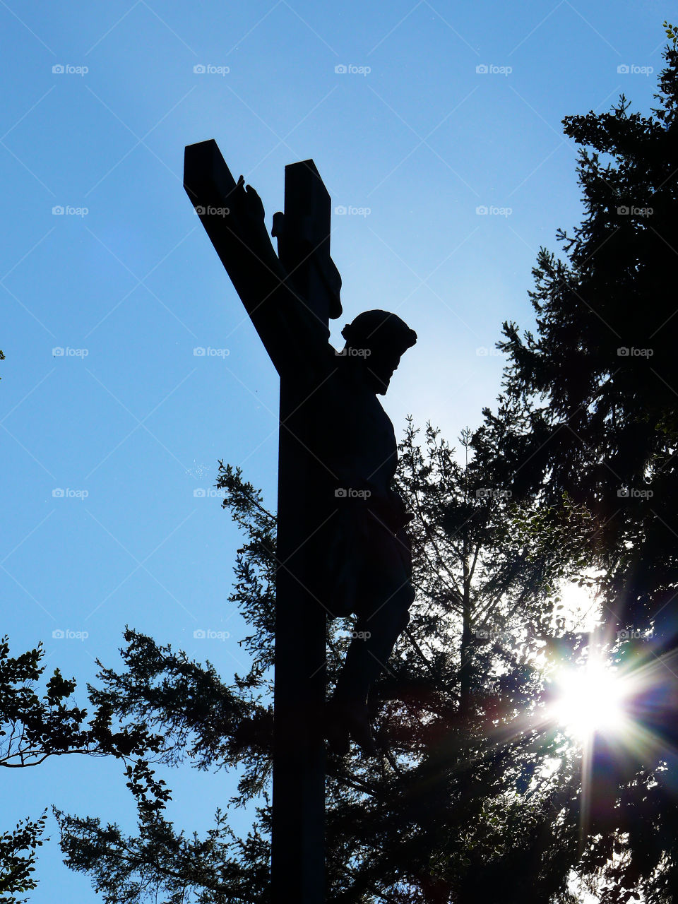 Low angle view of silhouette of Christ monument against trees in Starnberg, Germany.