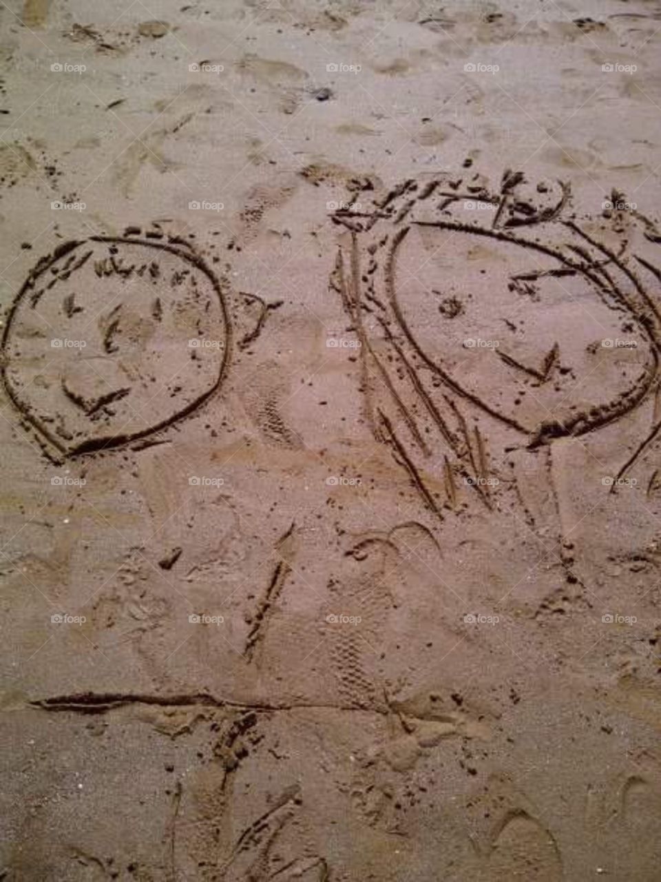 girl boy faces drawn in the sand