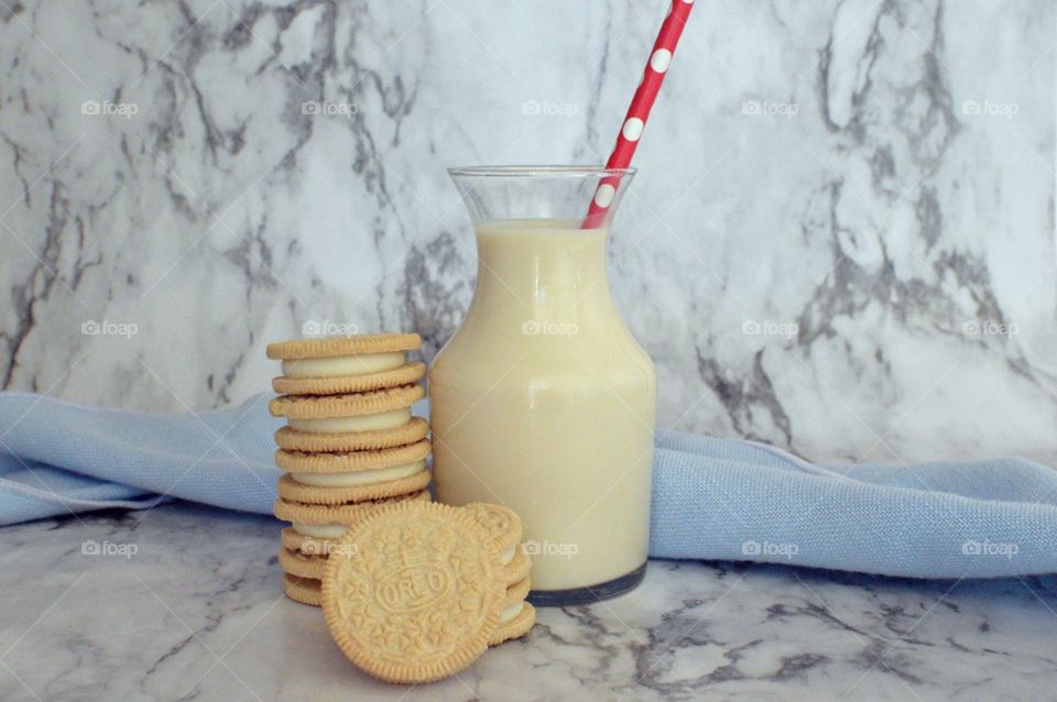 Oreo double stuff cookies stack next to a carafe of milk on a marble backdrop