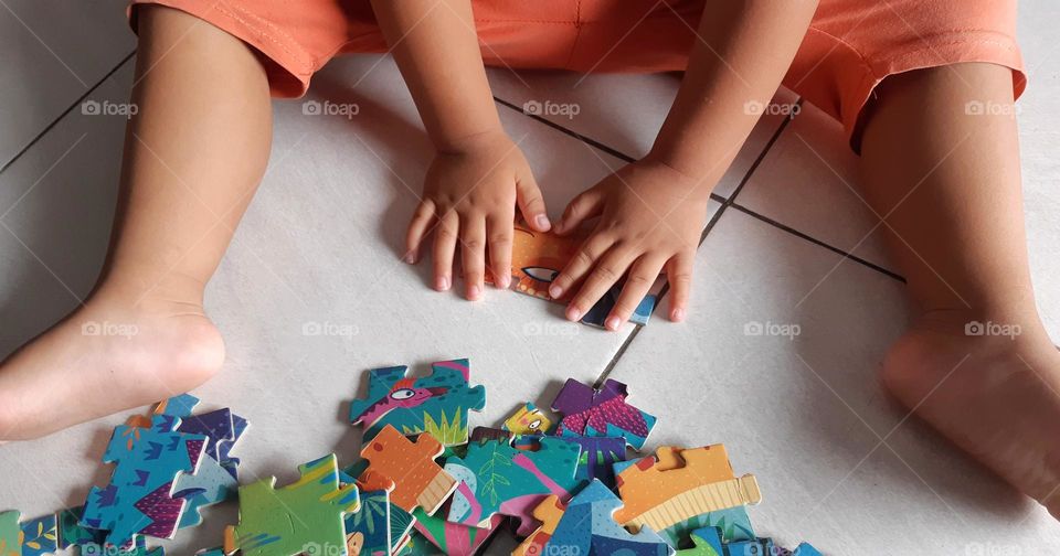 A kid playing puzzles on the floor
