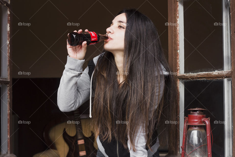 Beautiful woman drinking Coca-Cola on the window