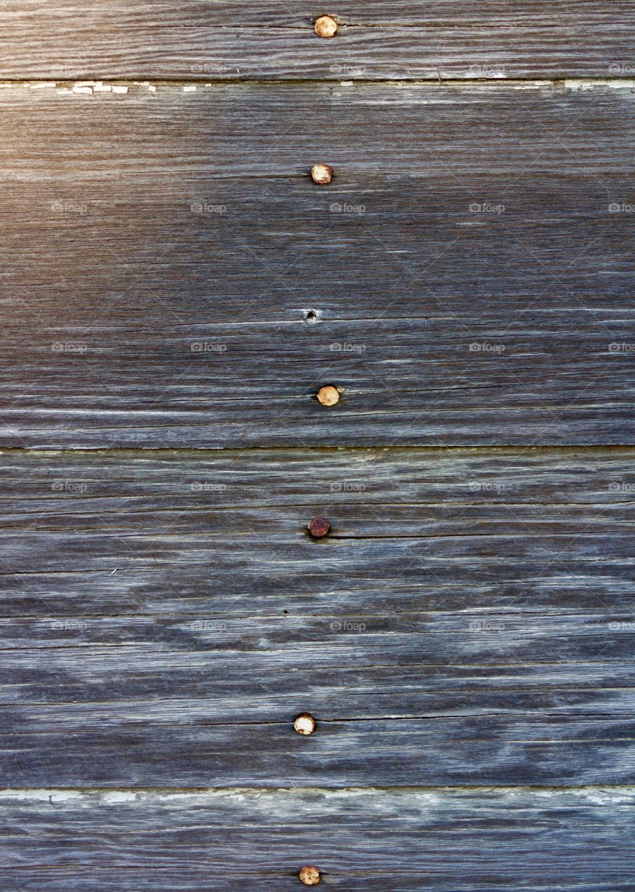 Weathered siding with rusty nails in a vertical line down the center
