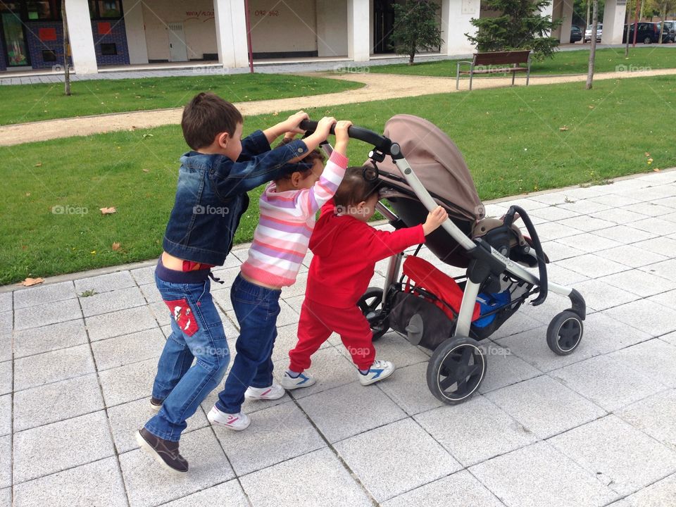 children pushing a baby carriage
