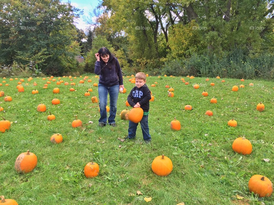 Mother and son with pumpkin patch in field
