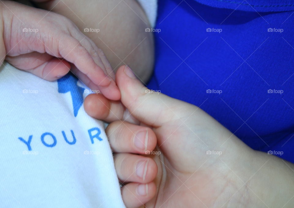 Tiny Hands. A toddler checks out the fingers of his newborn sibling. 