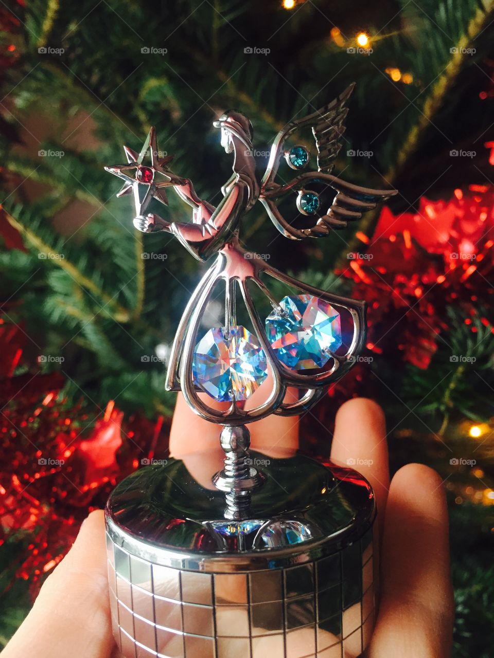 Hand holding spinning ballerina with swarowski crystals and Christmas tree in the background