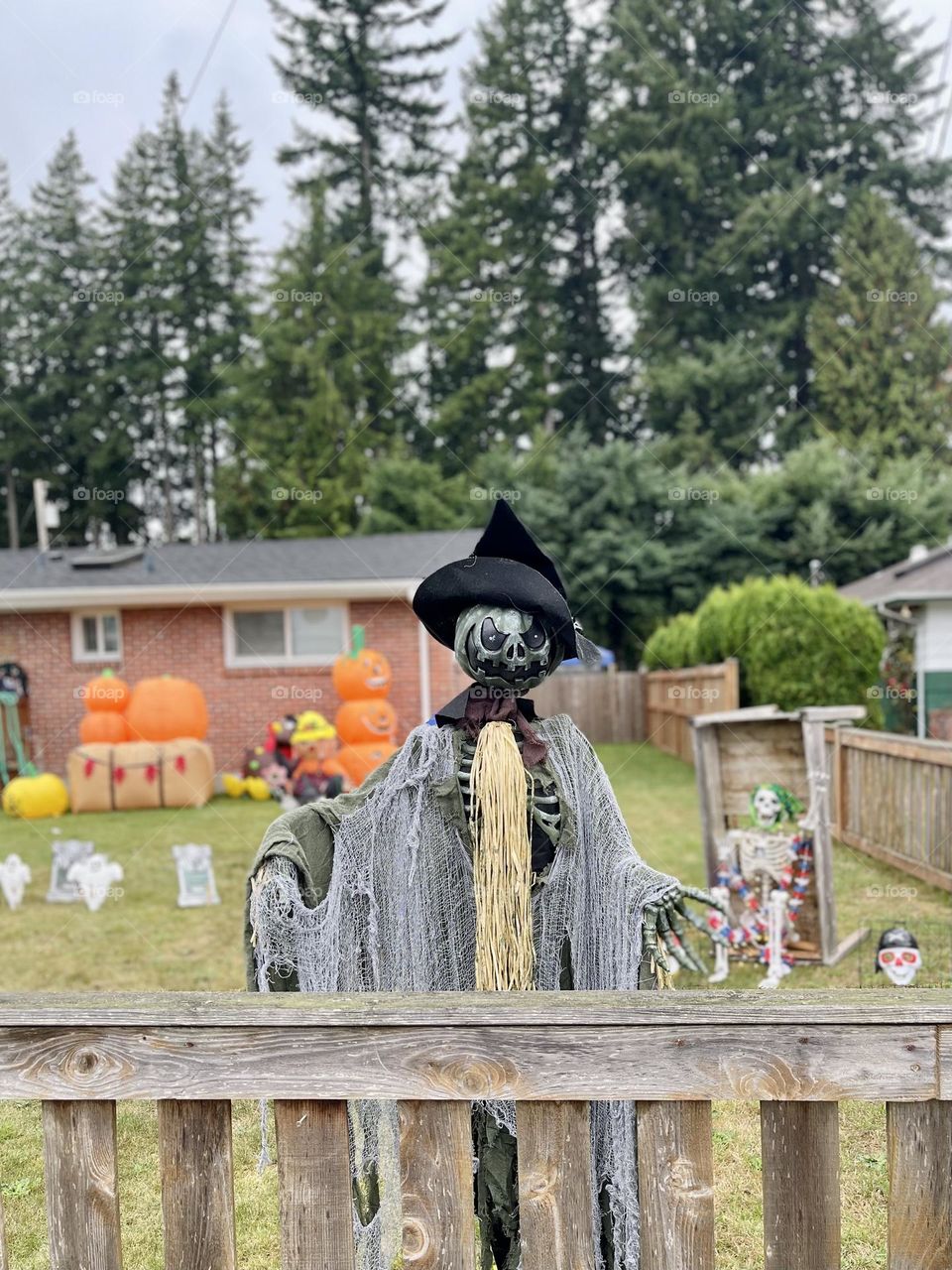 Scary pumpkin in the hat near the house fence 