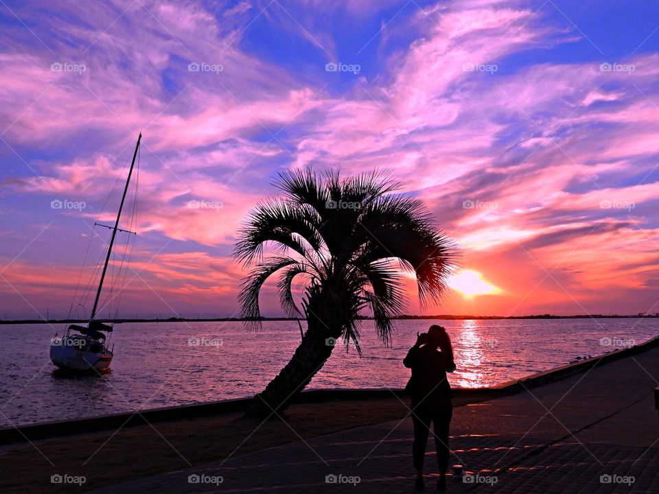 BEAUTIFUL SKY - mauve colored cloudy sky - The radiance of the beautIful mauve colored sky from the descending sunset was glorious to behold and increasing every moment in splendor.  A silhouette of a person and a palm tree are in the forefront. 