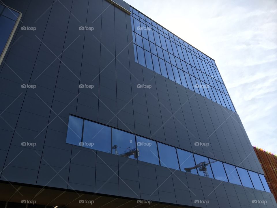 A closeup look of a tall building where the camera is pointing up to the bright, blue sky.