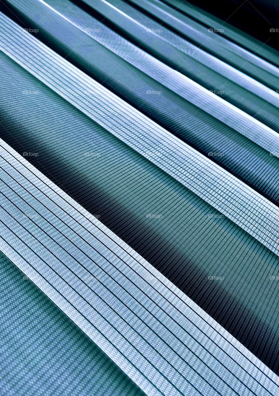 Textured diagonal alternating stripes creating an abstract pattern in blue-grey